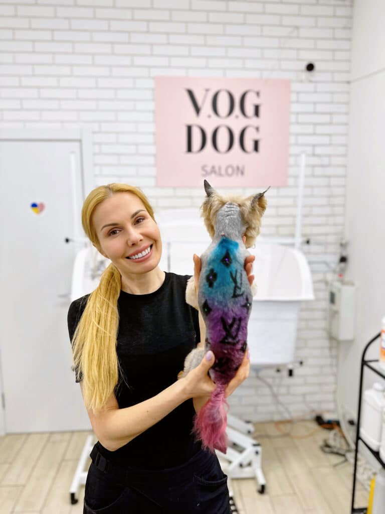 Дівчина з довгим світлим хвостом тримає руками під попу йорка, демонструючи креатив у грумінгу