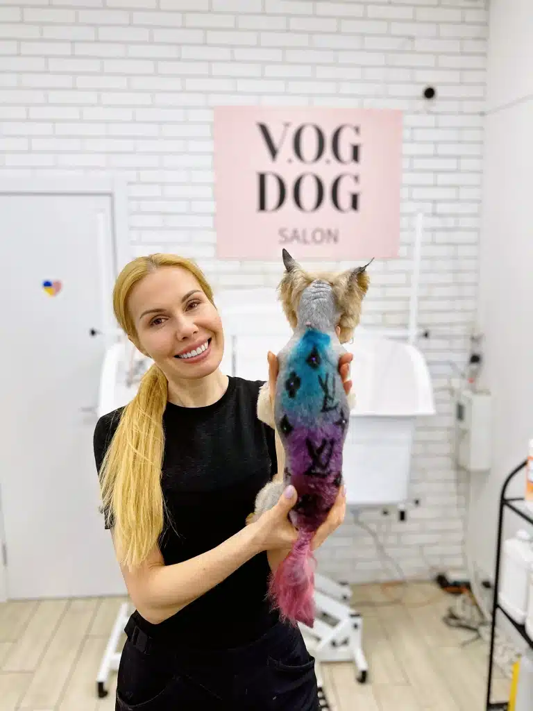 Дівчина з довгим світлим хвостом тримає руками під попу йорка, демонструючи креатив у грумінгу