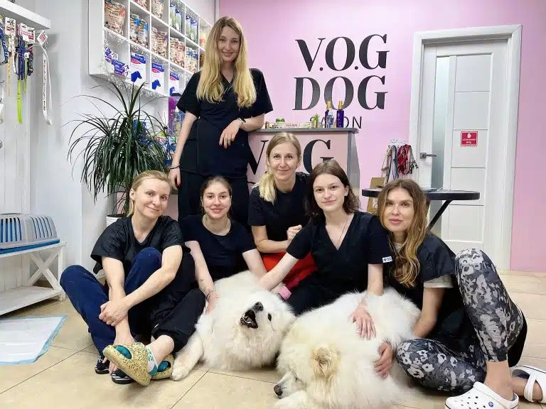 Виклад стоїть над студентами, які разом тримають білого великого пса