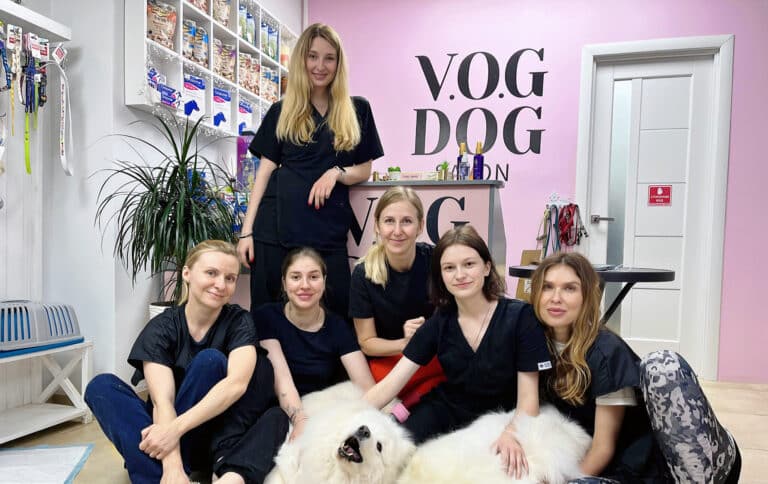 Виклад стоїть над студентами, які разом тримають білого великого пса