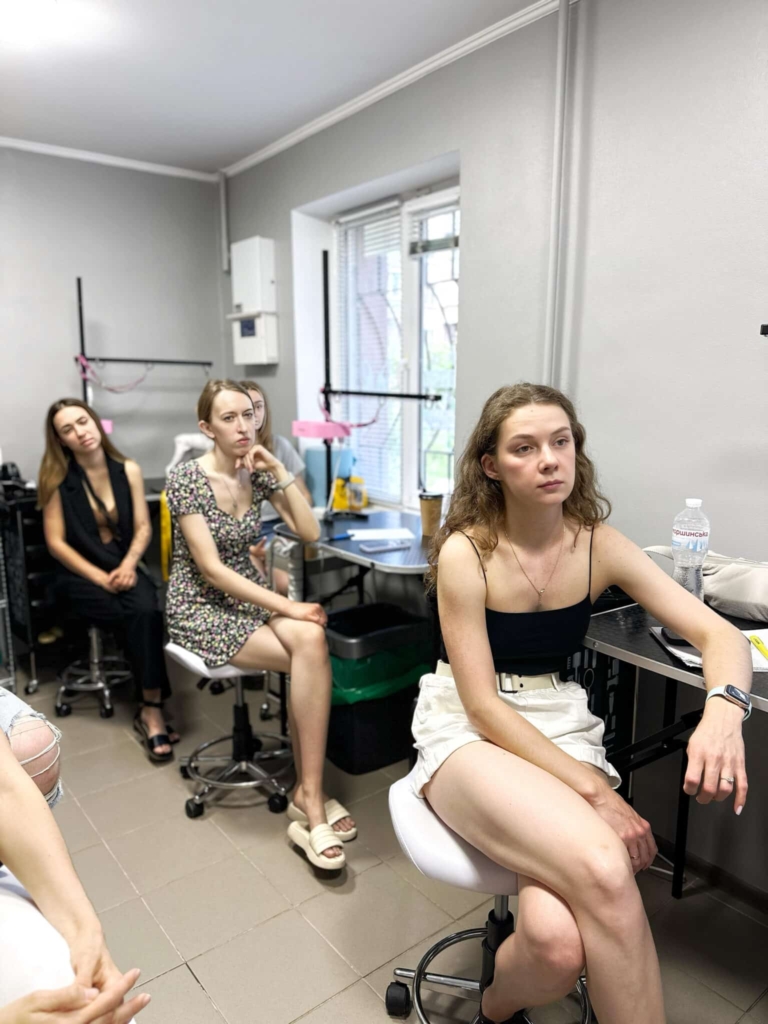 Дівчата сидять у вузькому приміщенні за грумерськими столами