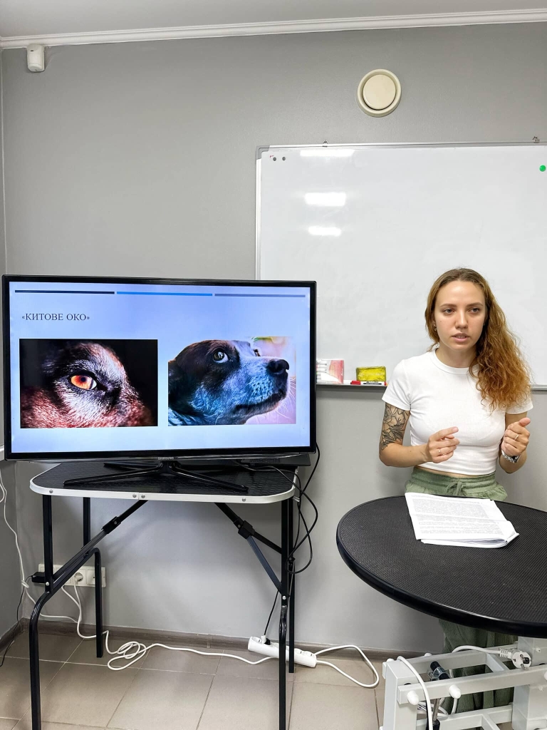 Ветеринар в білій футболці розповідає лекцію та демонструє зображення на екрані