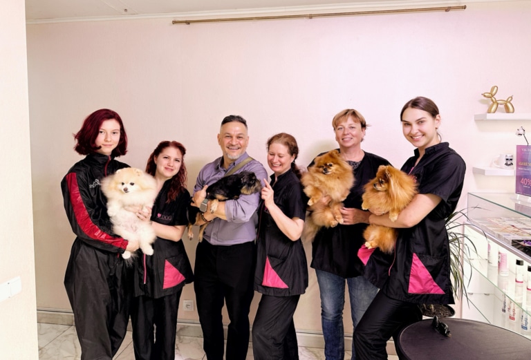 Грумери з тваринами на руках стали в рядок біля кремової стіни