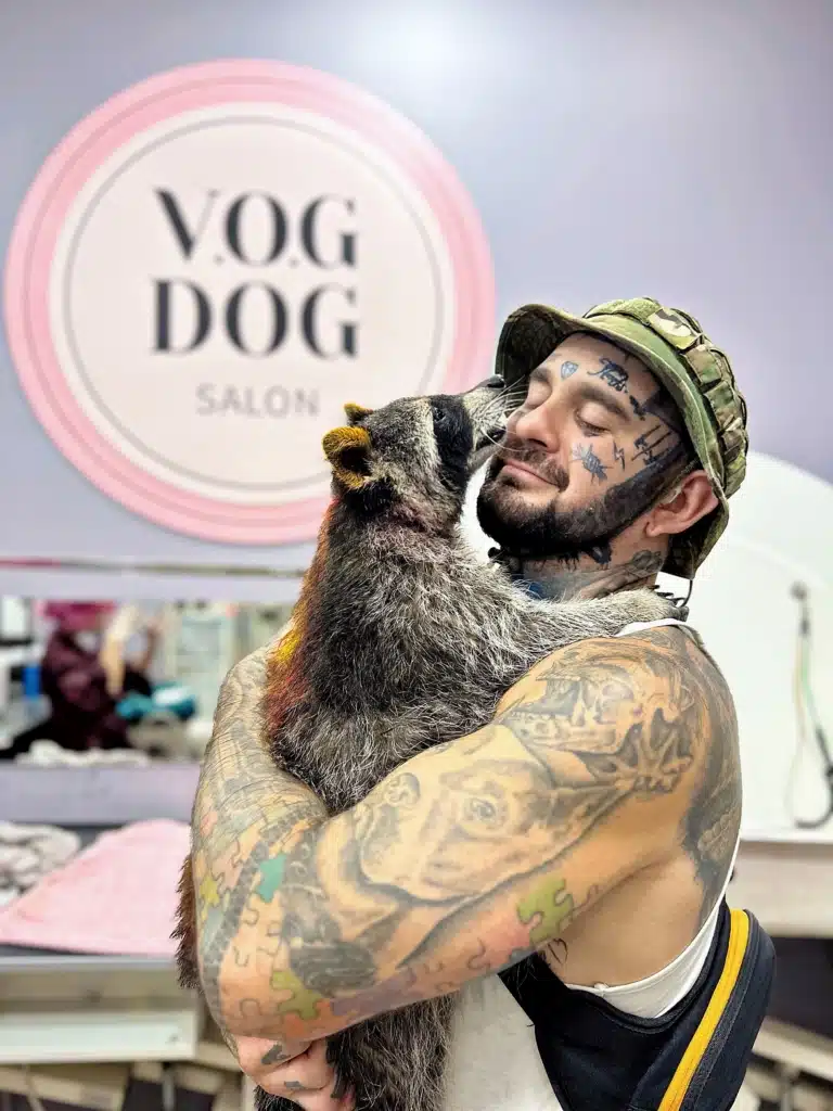 Власник у капелюсі тримає в руках єнота з жовтими вушками та спиною