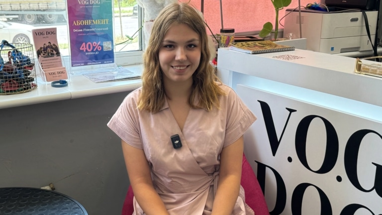 Дівчина в рожевій формі з льону має прикріплений чорний мікрофон