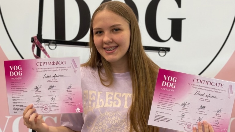 Дівчина з брекетами тримає в руках по сертифікату