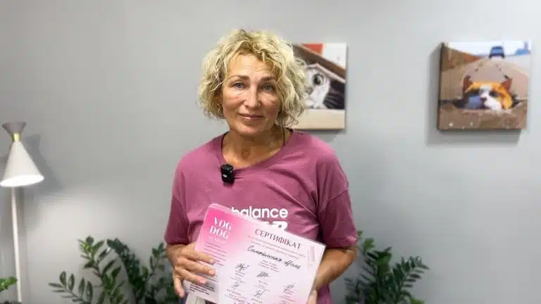 Жінка зі світлим коротким волоссям тримає правою рукою рожевий сертифікат