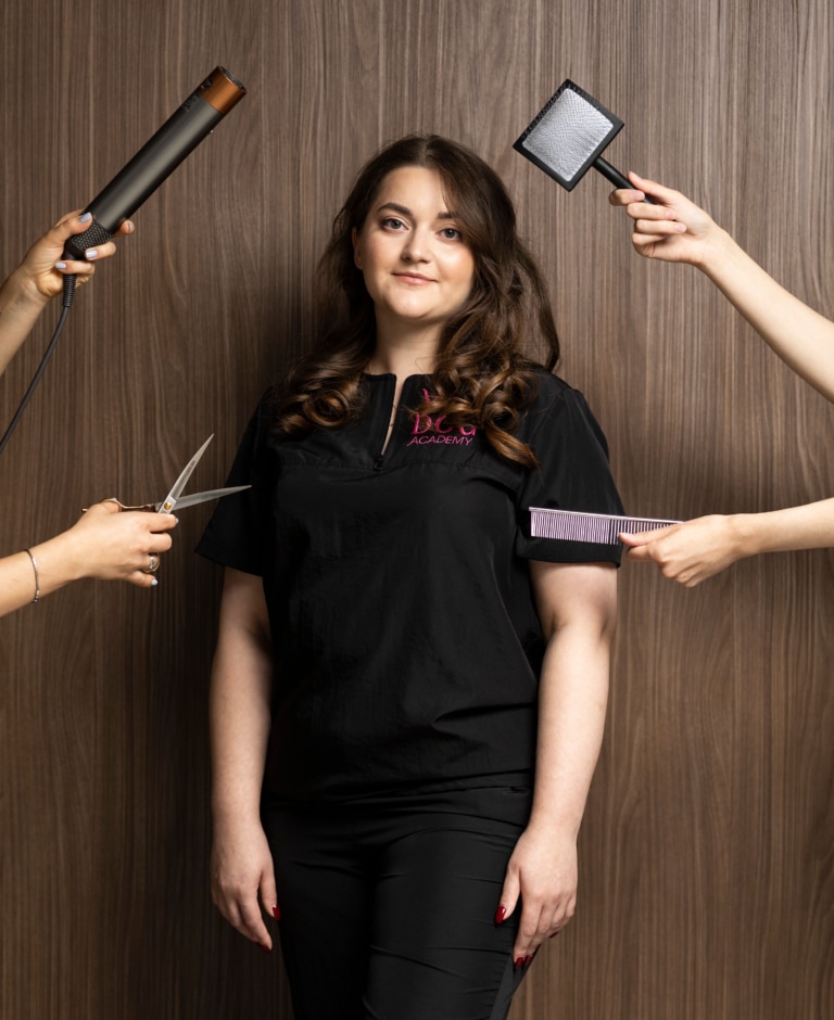 Перед дівчиною у формі руки тримають фен, ножиці, гребінець та слікер