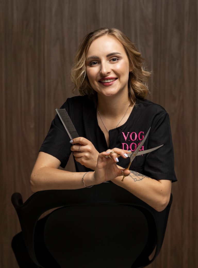 Дівчина тримає в лівій руці гребінець, а в правій - ножиці