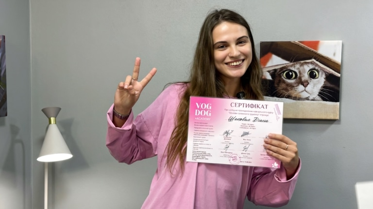 Дівчина в рожевій сорочці щиро посміхається після складеного іспиту