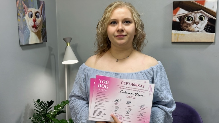 Дівчина зі світлим хвилястим волоссям демонструє отриманий сертифікат