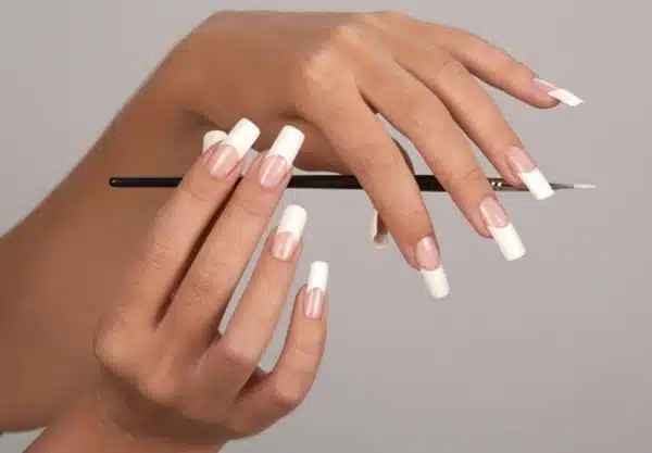 Дівчина з французьким манікюром тримає в руках пензлик