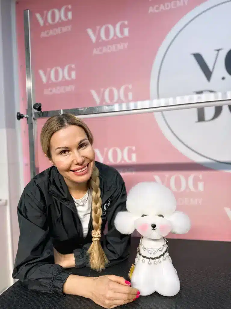 Грумерка всміхається поруч з штучною моделлю собаки