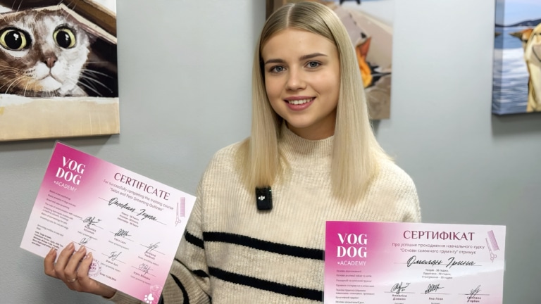 Дівчинка з білим волоссям тримає рожеві сертифікати