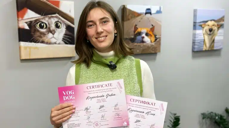 Молода дівчина в зеленому жилеті отримала диплом про успішне навчання на грумера