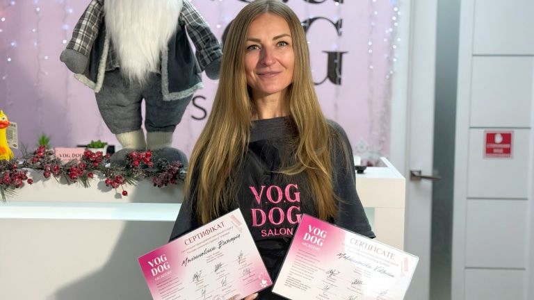 Дівчина з довгим волоссям демонструє отримані дипломи з курсів грумінгу