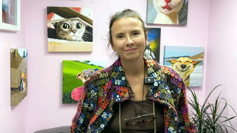 Усміхнена студентка курсів грумінгу стоїть посеред картин з тваринами