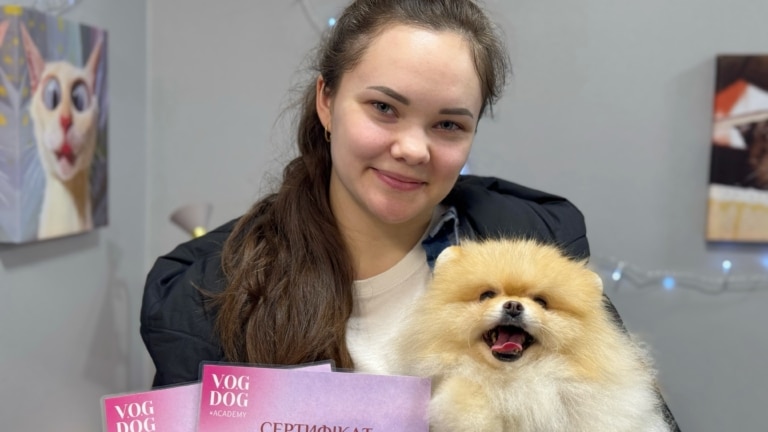 Дівчина з довгим хвостиком посміхається разом зі своїм підстриженим шпіцом