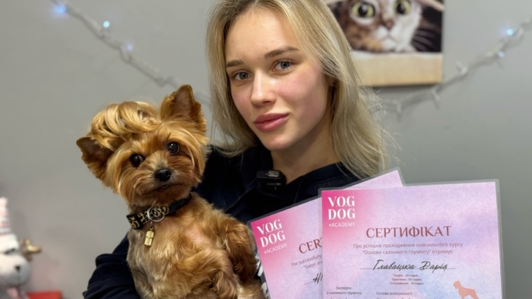 Дівчина з білим пофарбованим волоссям тримає в руках йорка та отримані сертифікати