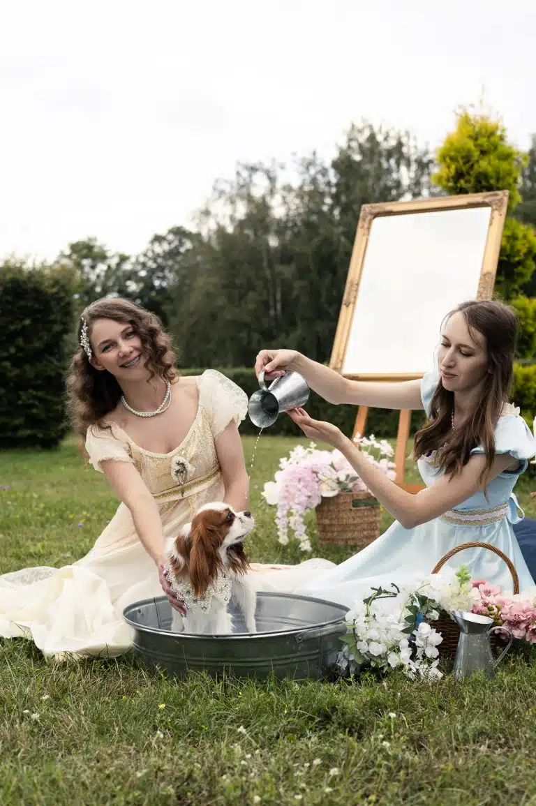 Дівчина в блакитній сукні ллє воду на спину спанієля з глечика