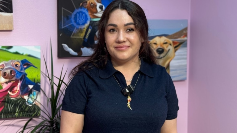 Дівчина в синій футболці має на шиї золоту прикрасу з пір'ям