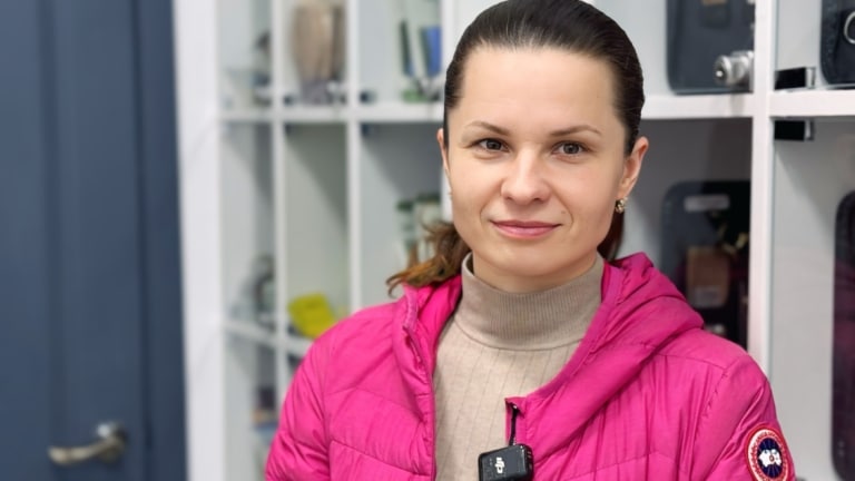 Дівчина у яскравій рожевій куртці стоїть спиною до грумерського інструменту