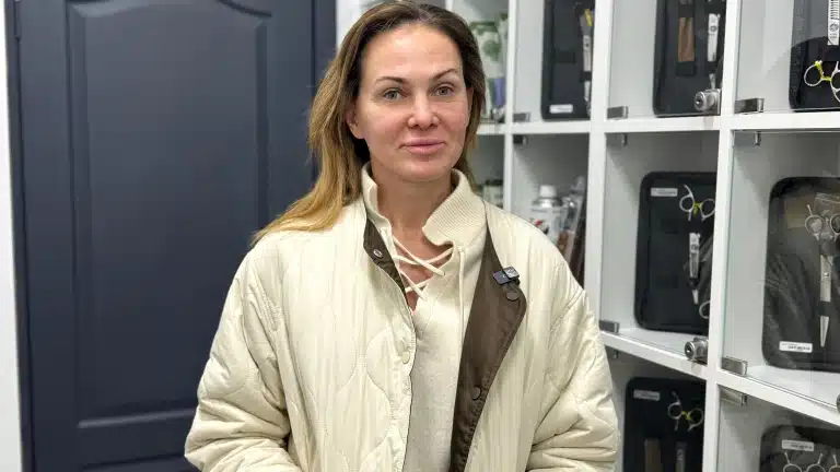 Дівчина в куртці кольору топленого масла стоїть біля грумерських ножиць