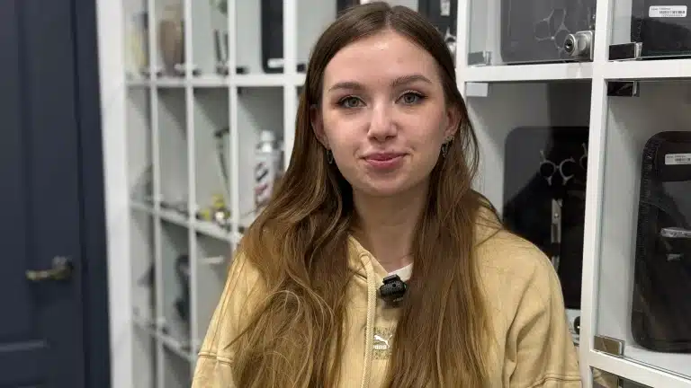 Дівчина з прямим волоссям закриває собою полиці з грумерськими ножицями