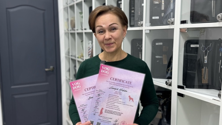 Жінка з тонкими намальованими бровами тримає в руках два рожевих сертифікати