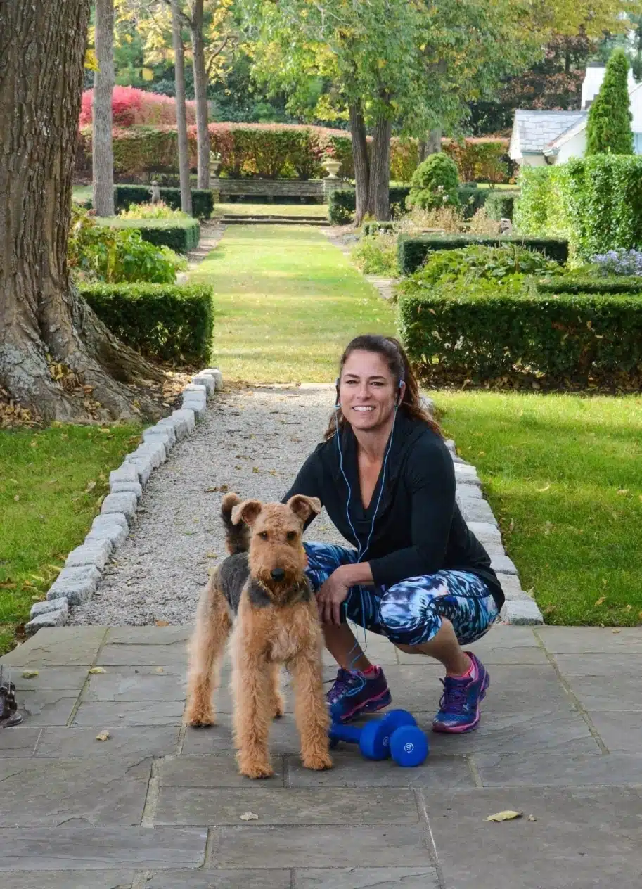 Дівчина з синіми навушниками присіла поруч з лейкленд-тер'єром