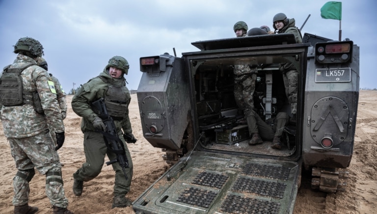 Військові з машиною на мокрому піску у вітряну холодну погоду