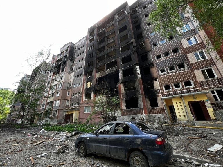 Знищений житловий будинок і синя автівка поруч з ним