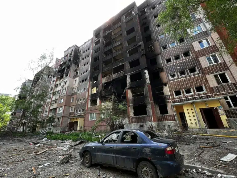 Знищений житловий будинок і синя автівка поруч з ним