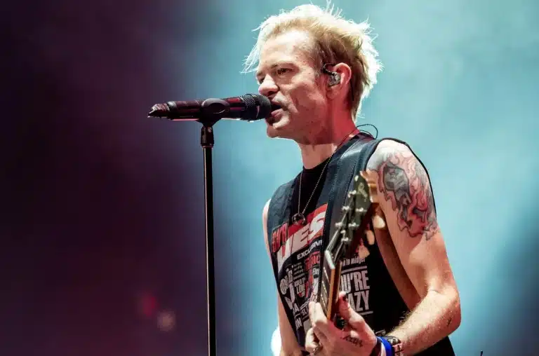 Чоловік з татуюванням на плечі співає з гітарою на концерті